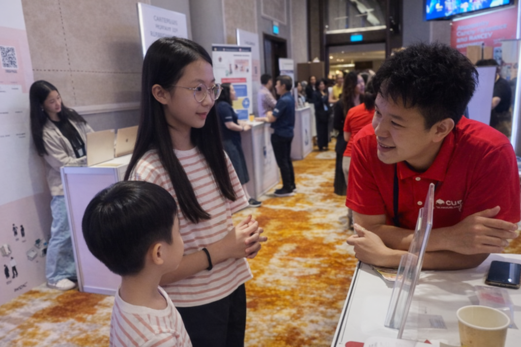 Elizabeth and Benjamin speaking with a charity representative at a booth during the State of Play event, learning about community needs and potential partnerships for SmolBoss.